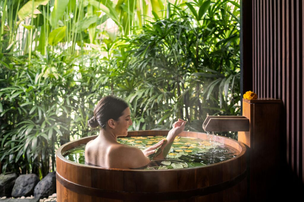 A woman enjoys a serene spa bath surrounded by lush greenery in Ubud, Bali.